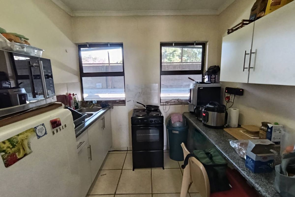 A compact kitchen featuring built-in cabinetry, a freestanding stove, and tiled flooring, offering a functional layout with potential for modernization.