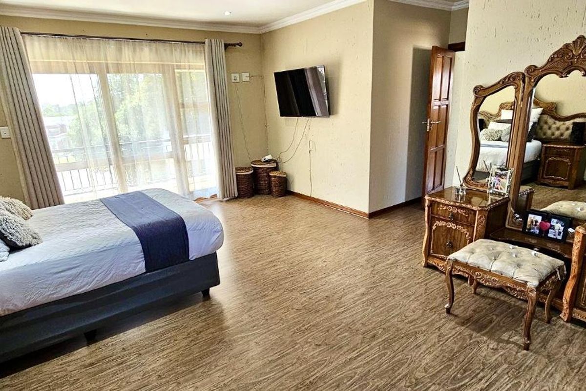 Spacious bedroom featuring wood-look flooring, sliding glass doors leading to a balcony, and neutral wall finishes.