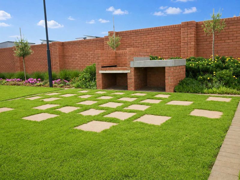 A well-maintained garden featuring a built-in brick braai, concrete countertop, and decorative paver stepping stones set within a lush lawn and brick boundary wall.