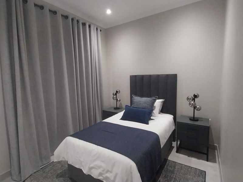 A well-maintained bedroom featuring neutral wall tones, recessed downlighting, and tiled flooring, offering a clean and comfortable living space.