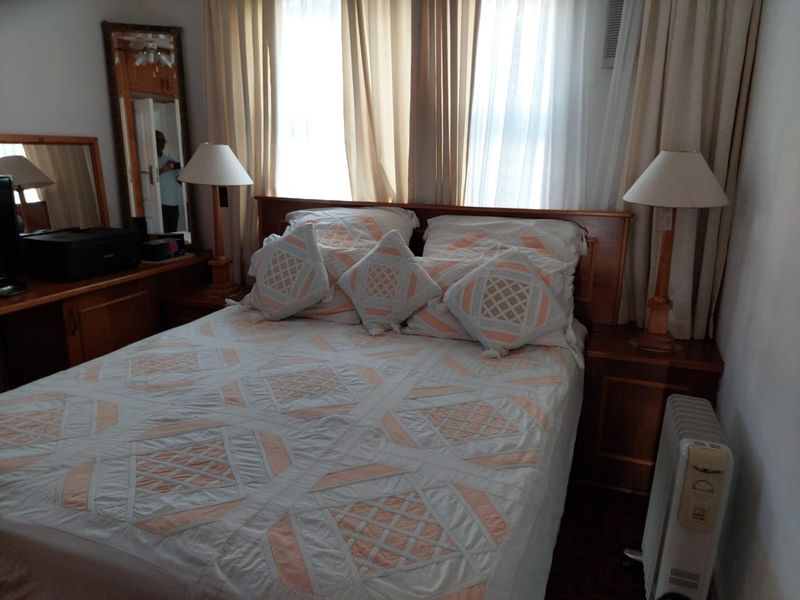 A bedroom featuring built-in wooden cabinetry and a window-mounted air conditioning unit, providing a functional and traditional living space.