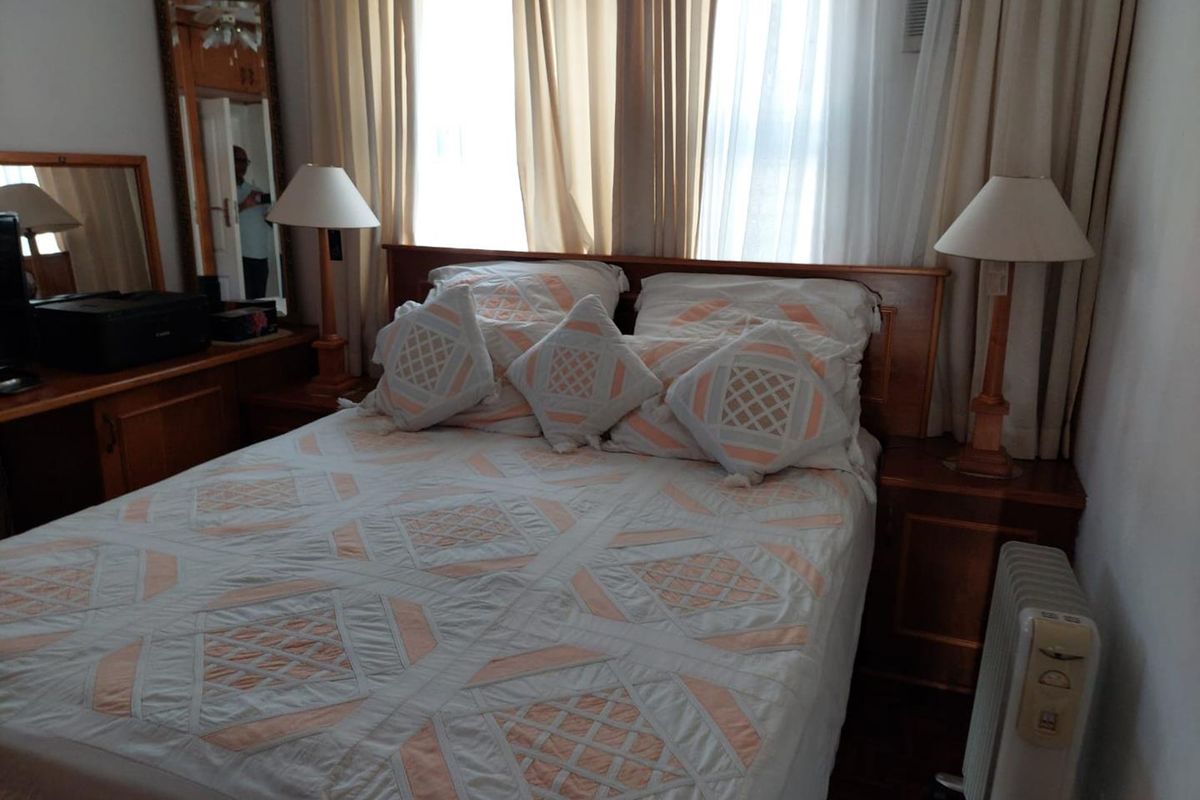A bedroom featuring built-in wooden cabinetry and a window-mounted air conditioning unit, providing a functional and traditional living space.