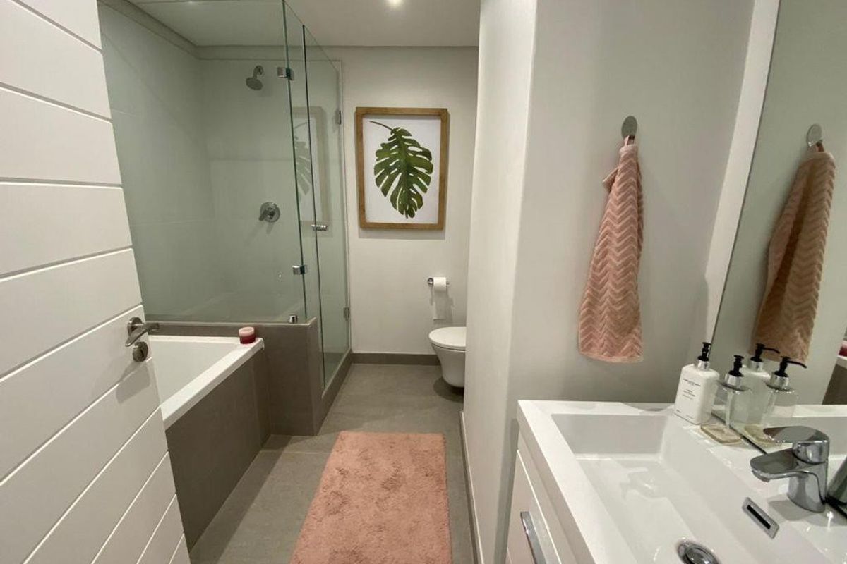 Modern bathroom featuring a glass-enclosed shower, built-in bathtub, wall-mounted toilet, and a sleek vanity basin with chrome fixtures.