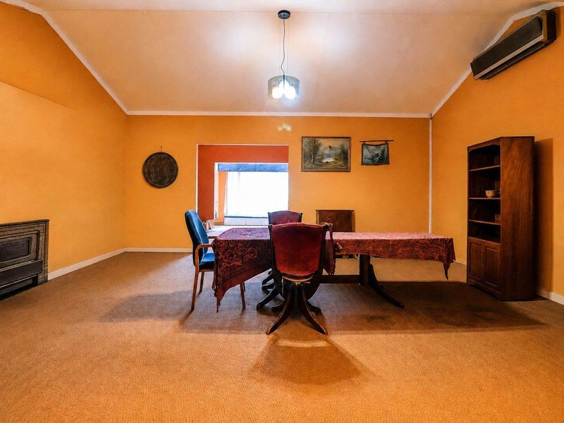 Spacious living room featuring a vaulted ceiling, built-in fireplace, and wall-mounted air conditioning unit, offering a versatile layout for comfortable family living.