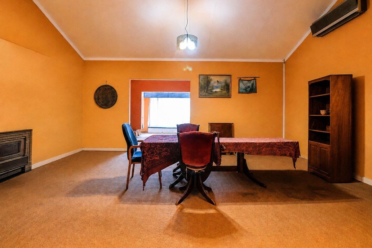 Spacious living room featuring a vaulted ceiling, built-in fireplace, and wall-mounted air conditioning unit, offering a versatile layout for comfortable family living.