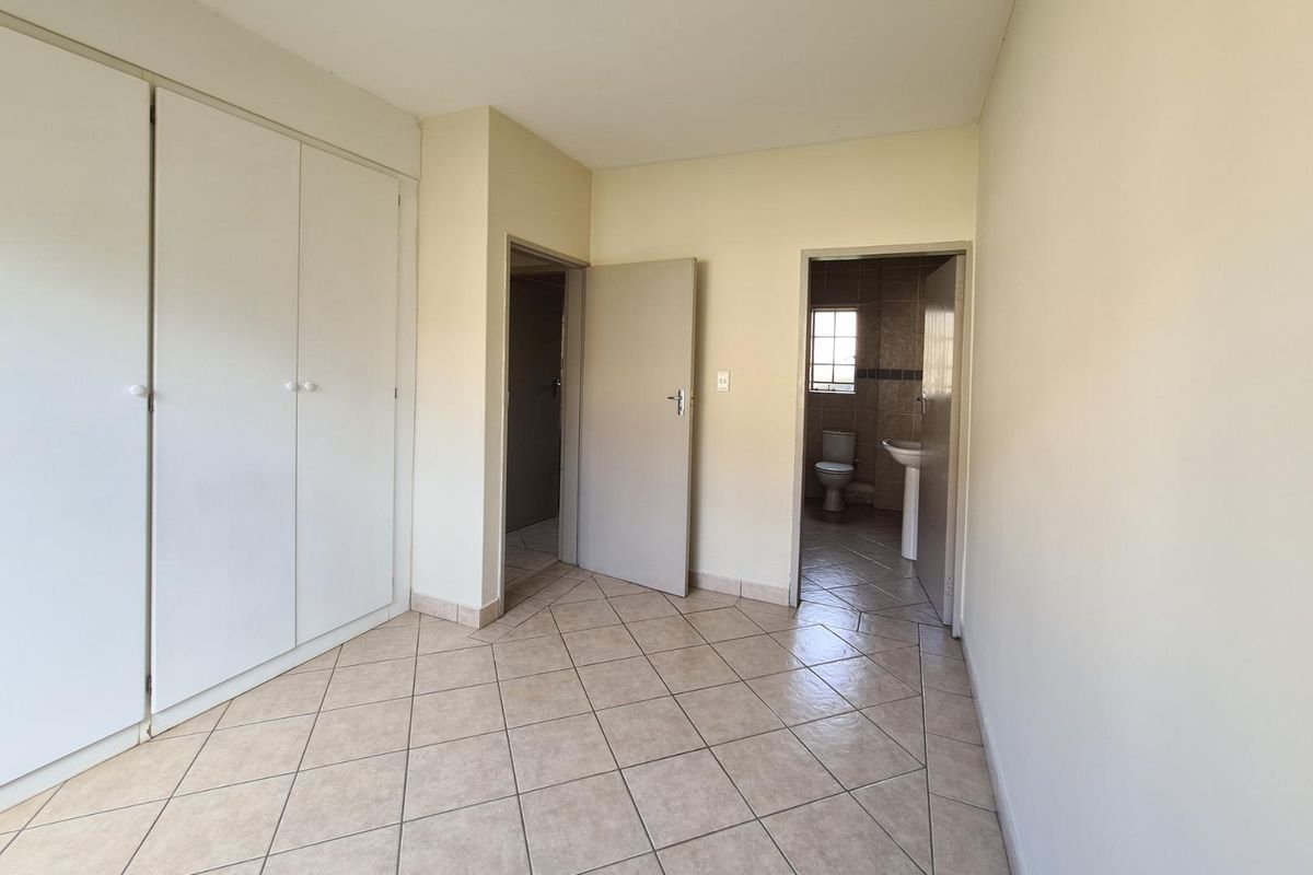 A bedroom featuring built-in cupboards, tiled flooring, and direct access to an en-suite bathroom.