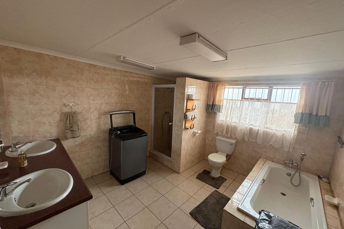Spacious bathroom featuring a double vanity, built-in bathtub, separate shower enclosure, and toilet, with tiled walls and flooring throughout.
