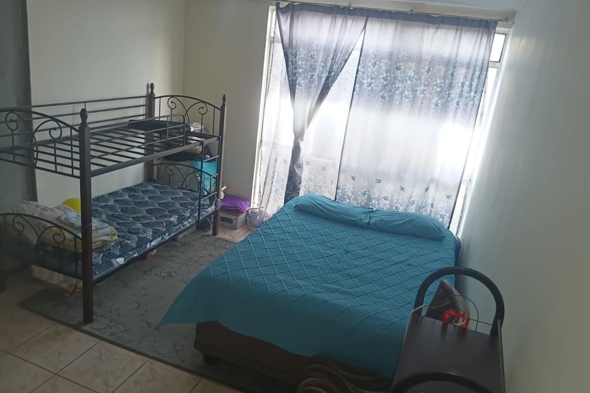 A functional bedroom featuring tiled flooring and a large sliding glass door that provides natural light.