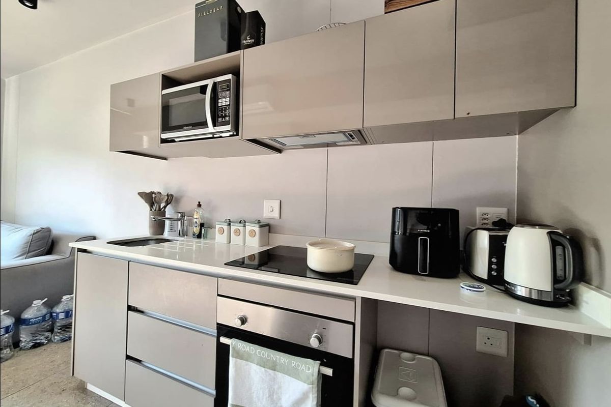 Modern compact kitchen featuring high-gloss cabinetry, integrated appliances including an oven and hob, and a clean quartz countertop.