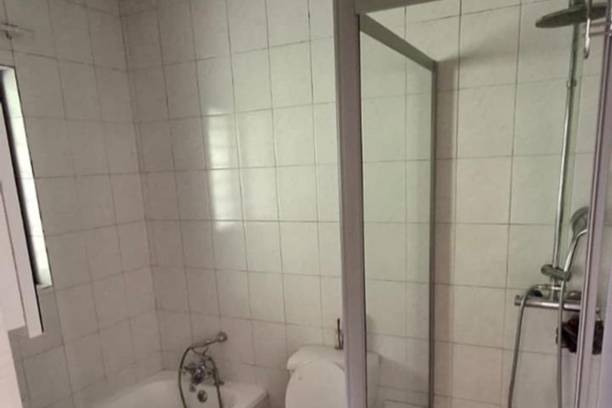 A functional bathroom featuring a bathtub, separate shower enclosure, and toilet, finished with white wall tiles and floor tiling.