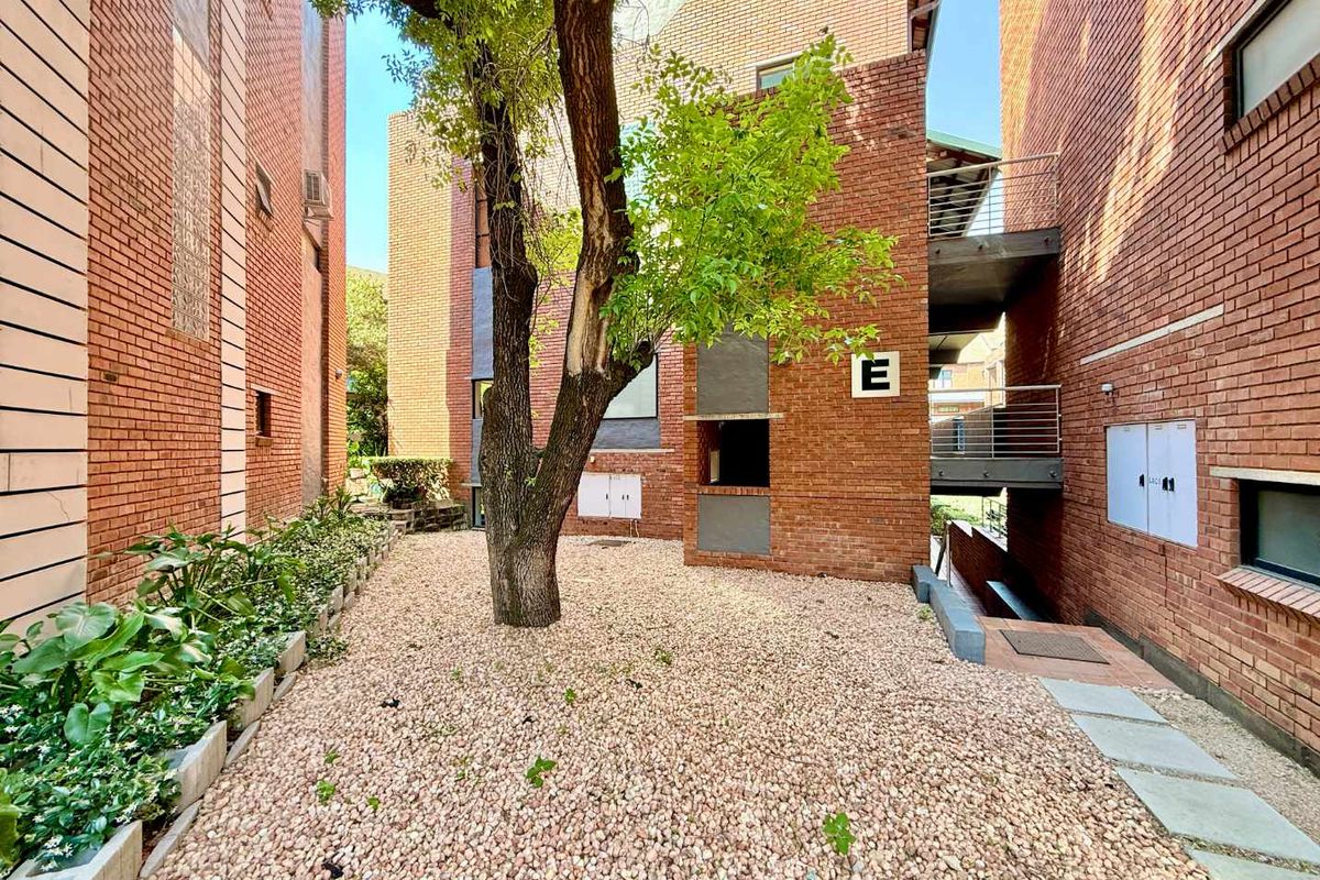 A view of the apartment complex courtyard featuring exposed brick facades, gravel landscaping, and metal stairwell access.
