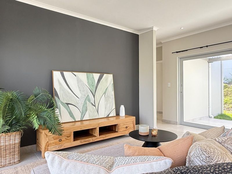 A bright living room featuring a dark accent wall, tiled flooring, and a large sliding glass door providing access to the outdoor area.