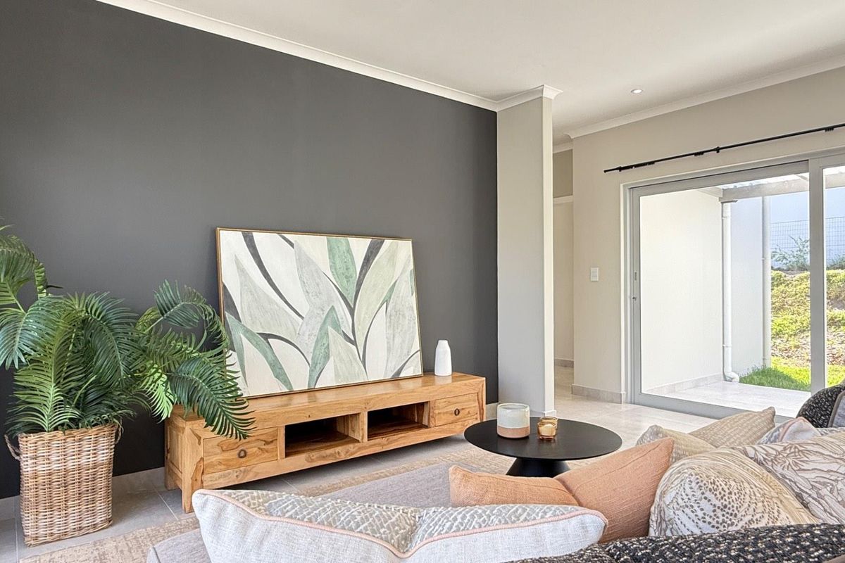 A bright living room featuring a dark accent wall, tiled flooring, and a large sliding glass door providing access to the outdoor area.