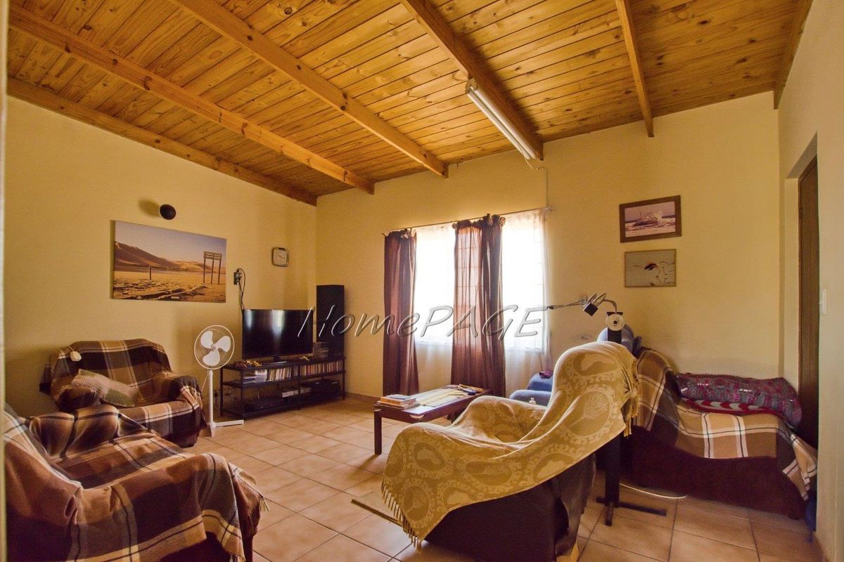A living room featuring exposed timber beam ceilings and tiled flooring, providing a functional and rustic interior space.