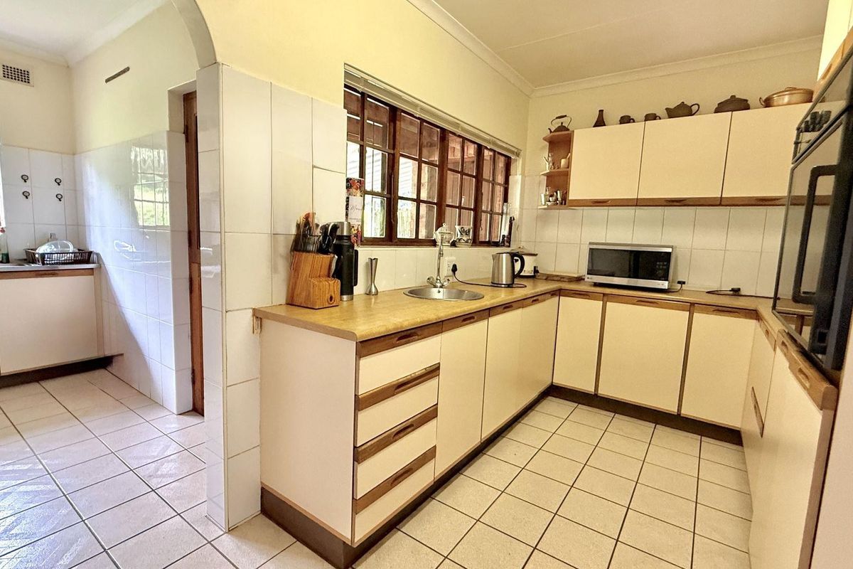 A functional kitchen featuring light-toned cabinetry, tiled flooring, a built-in oven, and a double-basin sink with a window view.