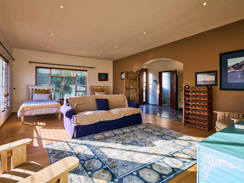 Spacious bedroom featuring laminate flooring, recessed downlighting, and an arched entryway leading to an adjacent tiled area.