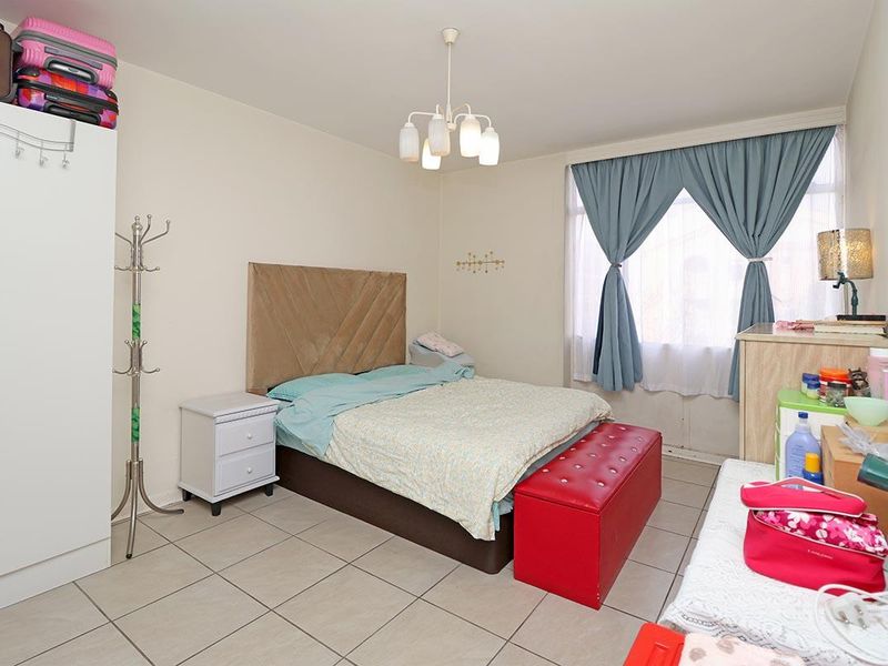 A functional bedroom featuring tiled flooring, a central ceiling light fixture, and a built-in wardrobe, offering a neutral base for personalization.