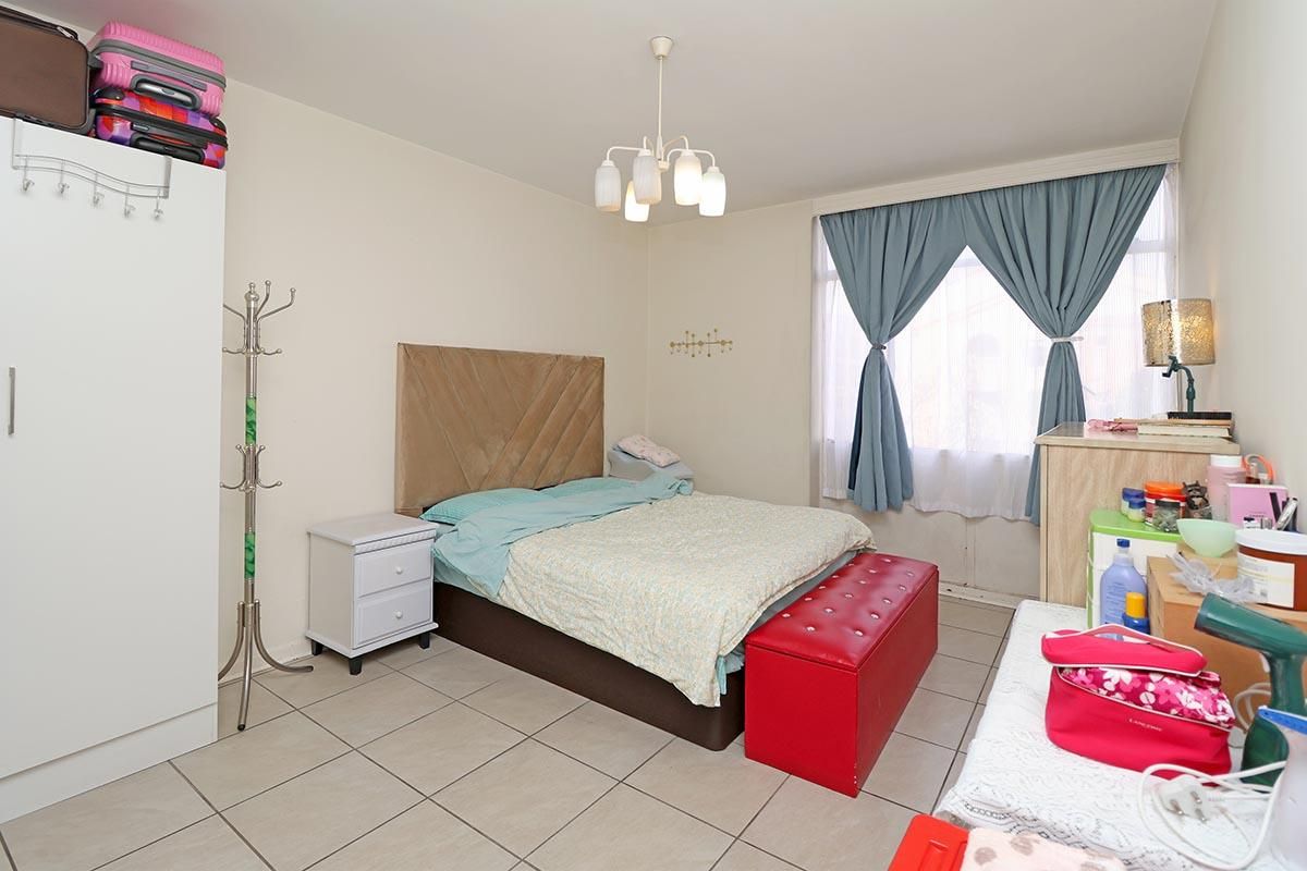 A functional bedroom featuring tiled flooring, a central ceiling light fixture, and a built-in wardrobe, offering a neutral base for personalization.