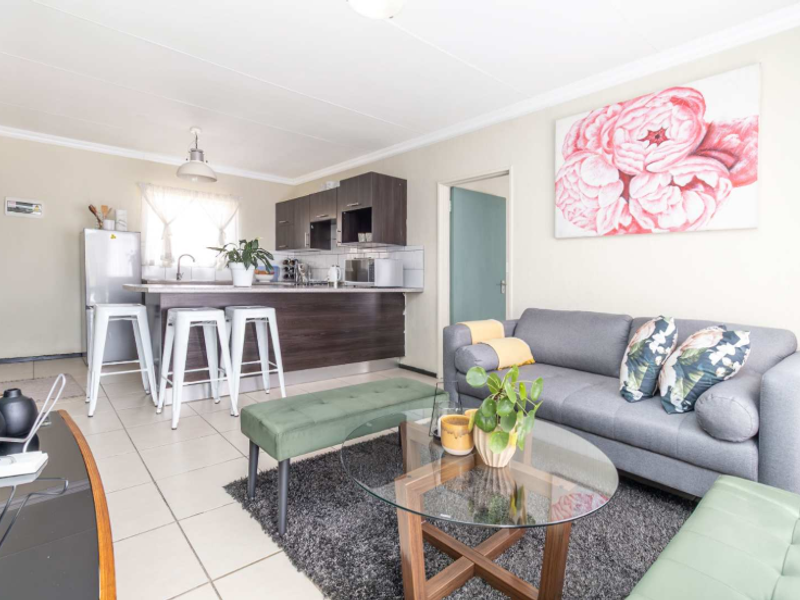 Open-plan living area featuring a functional kitchen with dark cabinetry and tiled flooring, seamlessly connected to a comfortable lounge space.