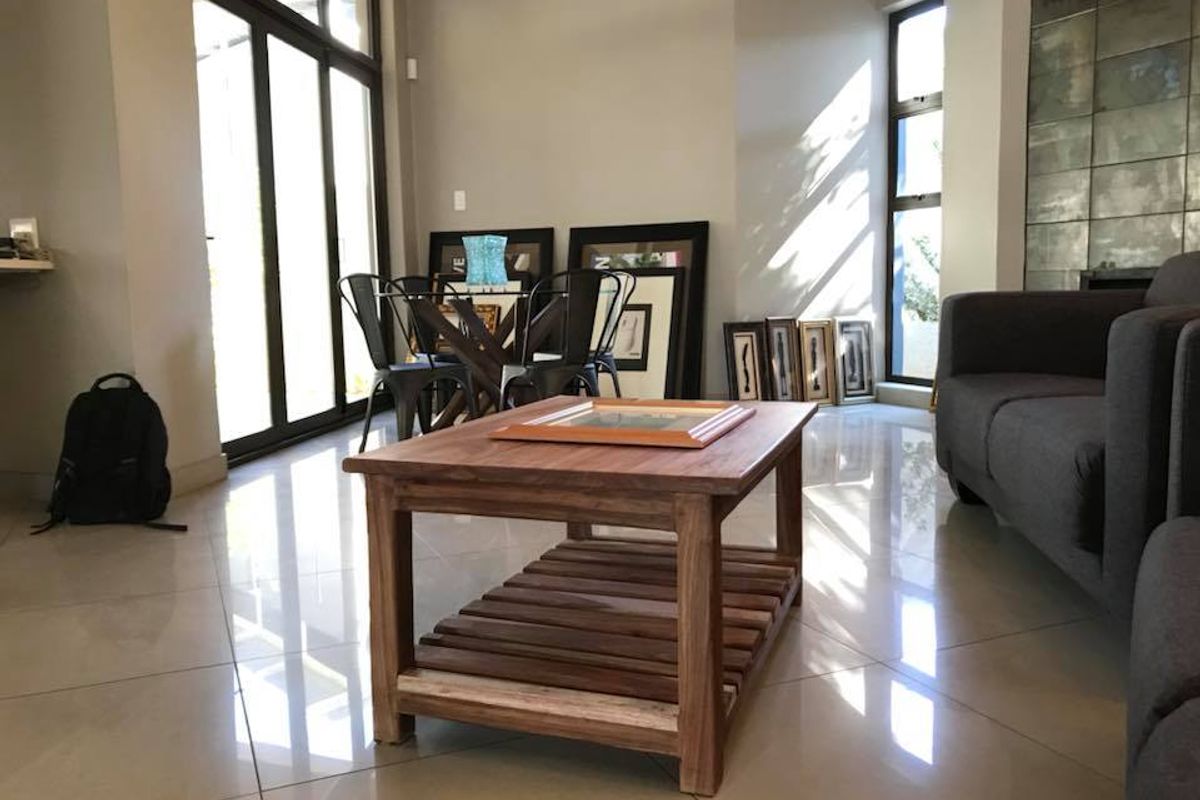 A bright and spacious living area featuring large glass sliding doors, expansive windows, and polished tiled flooring with a modern feature wall.