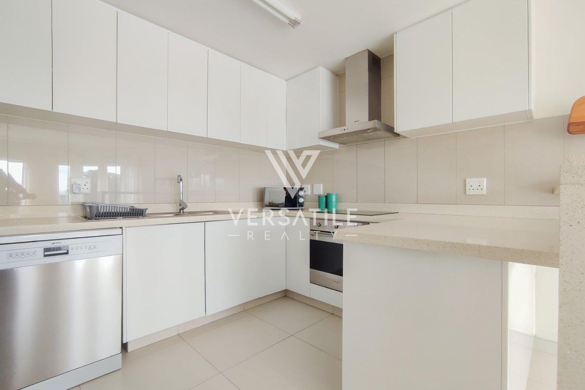 A clean, modern kitchen featuring white cabinetry, stone countertops, integrated appliances, and neutral tiled flooring.