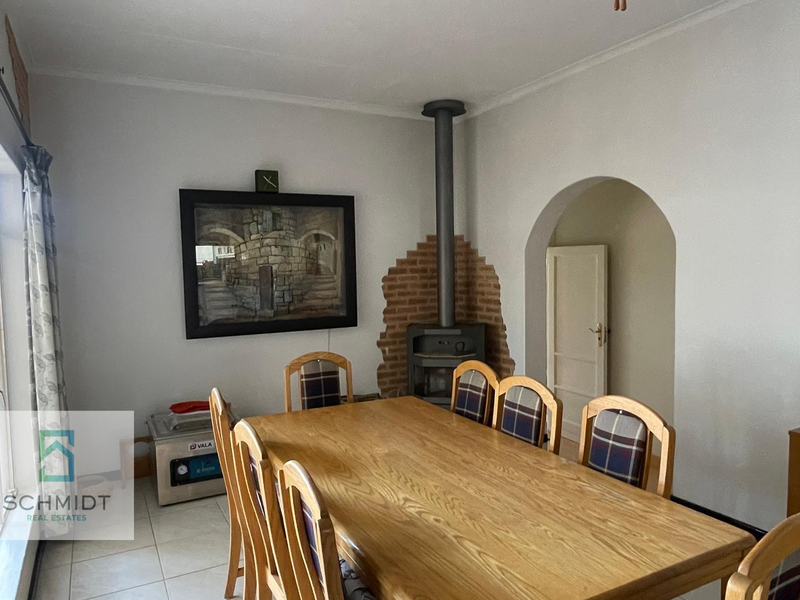 Dining room featuring tiled flooring, an arched doorway, and a central freestanding fireplace with an exposed brick feature wall.