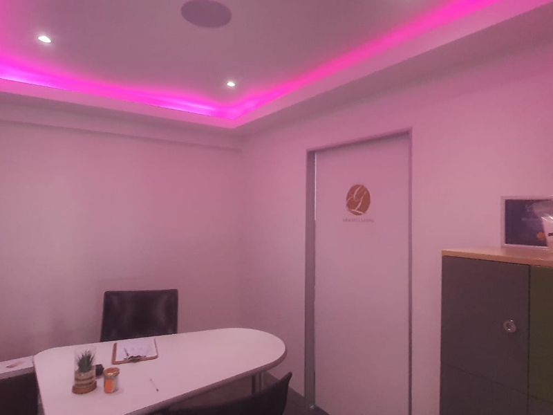 A professional office space featuring modern recessed ceiling lighting with integrated cove accent lighting and built-in storage cabinetry.
