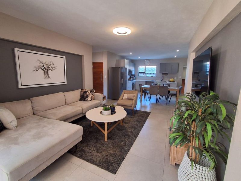 Spacious open-plan living area featuring a modern kitchen with island, tiled flooring, and neutral finishes, creating a seamless flow between kitchen and lounge.
