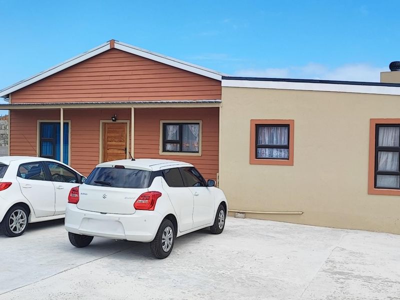 Front elevation of a single-story house featuring a combination of timber cladding and rendered walls, with a concrete driveway and covered entrance porch.