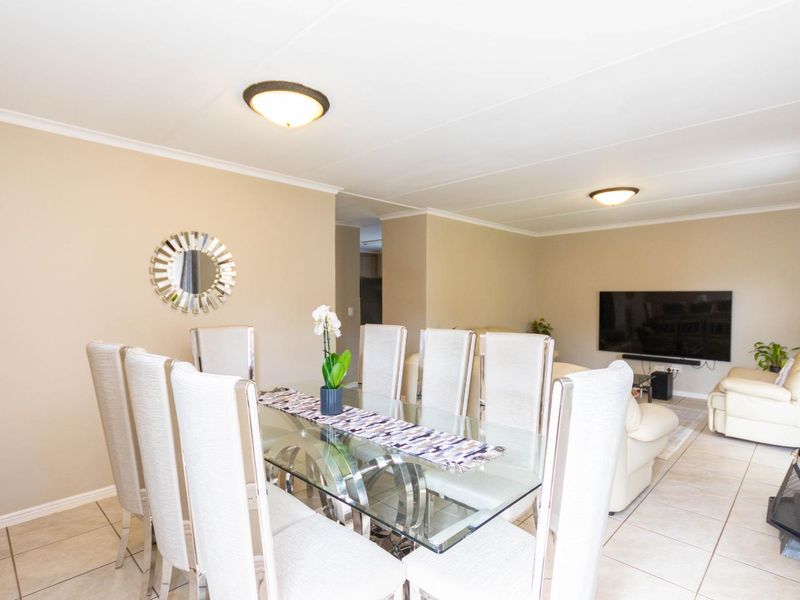 An open-plan living and dining area featuring neutral wall tones, tiled flooring, and flush mount ceiling lighting.