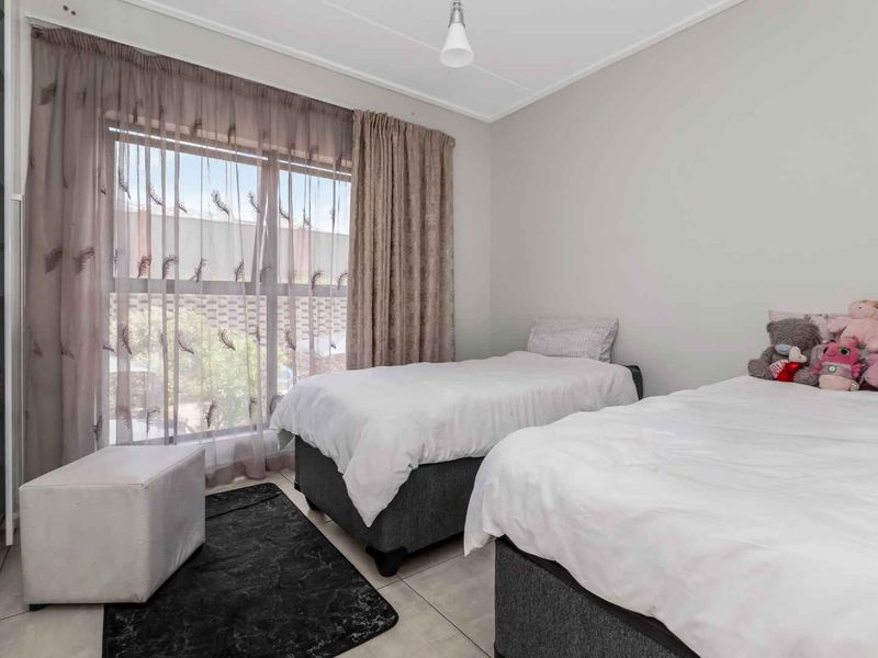 A functional bedroom featuring tiled flooring, a built-in cupboard, and a large sliding glass door that provides natural light.