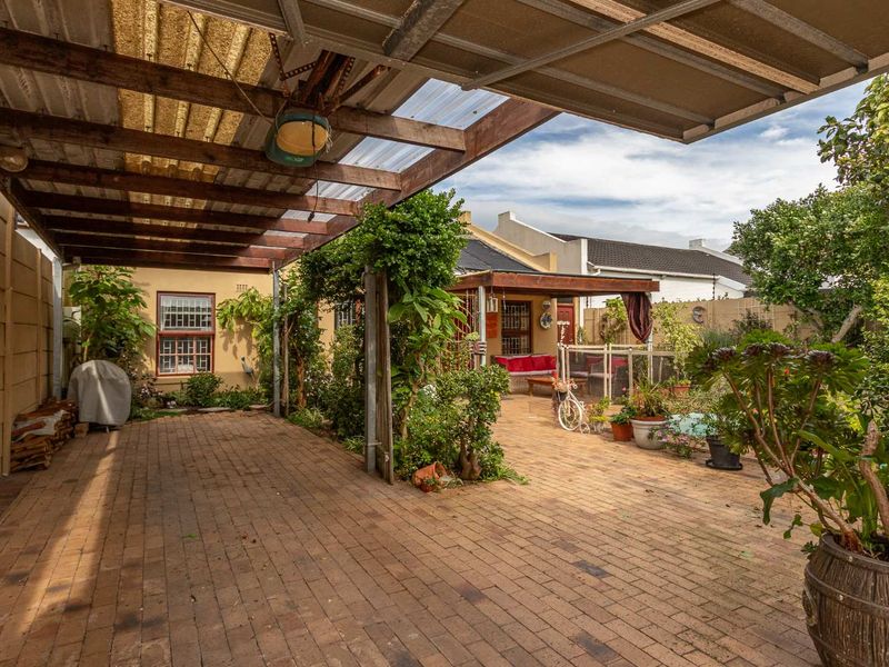 A spacious outdoor patio area featuring brick paving and a covered timber pergola structure, providing a functional space for outdoor living and entertainment.