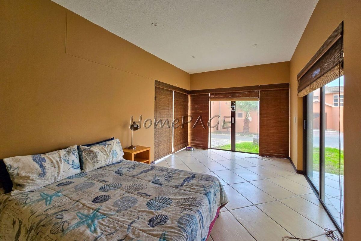 Spacious bedroom featuring large sliding glass doors with bamboo blinds, tiled flooring, and recessed ceiling lighting, offering direct access to the exterior.