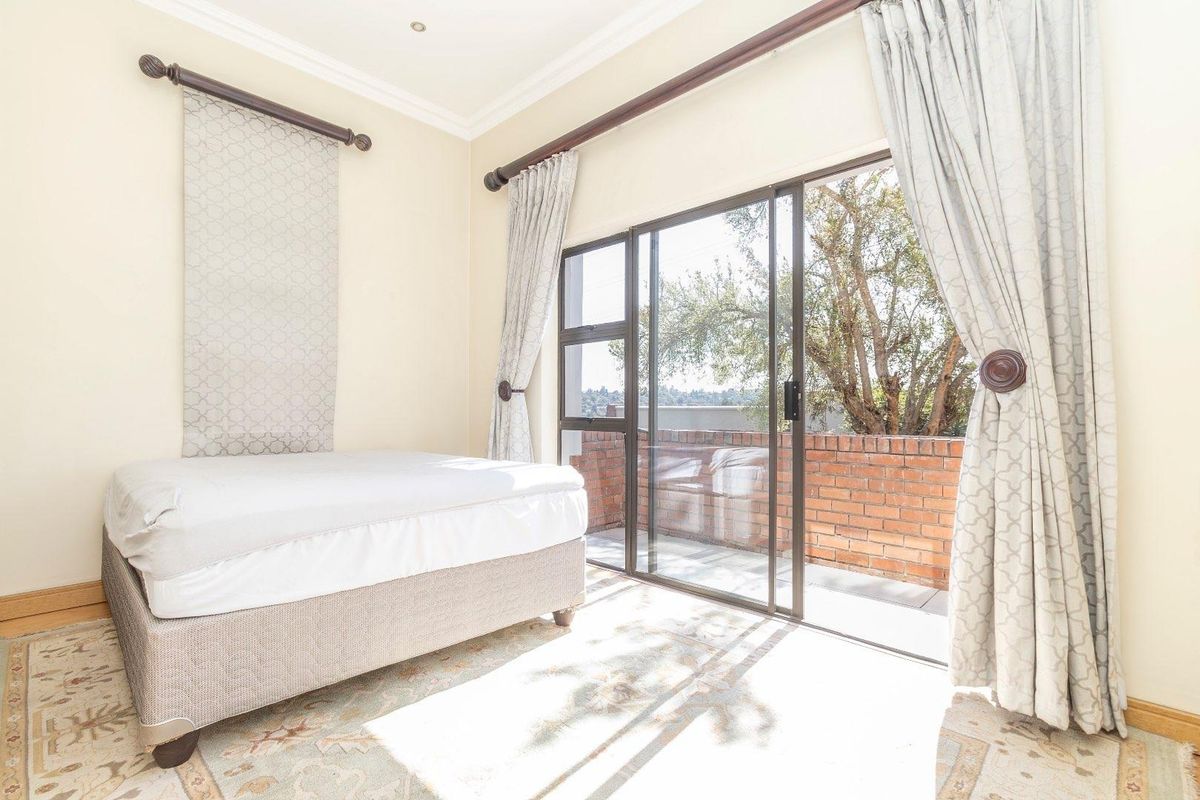 A bright bedroom featuring a sliding glass door that opens onto a private balcony, complemented by coved ceilings and recessed lighting.