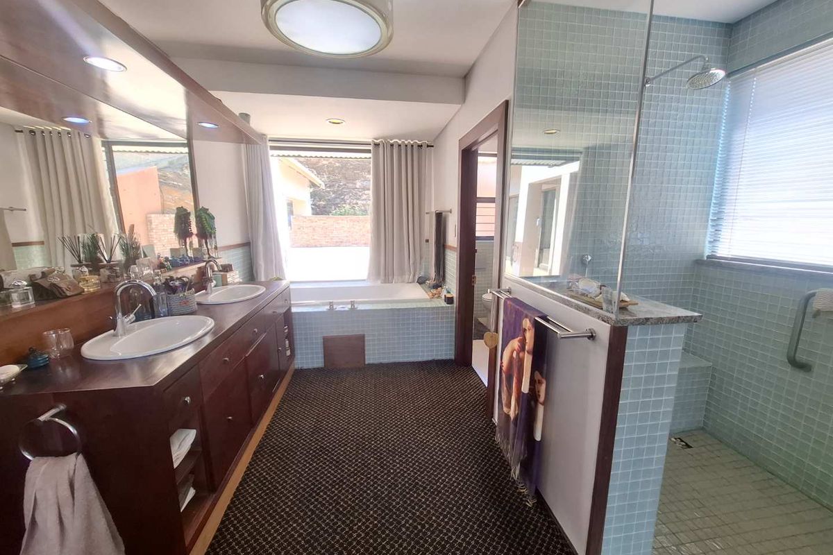 Spacious bathroom featuring a double vanity, built-in bathtub, and a separate walk-in shower with mosaic tiling.