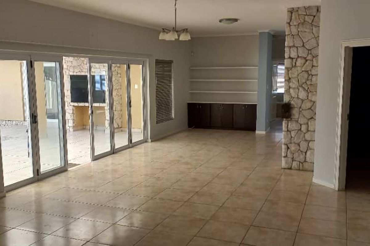 Spacious living area featuring tiled floors, stone-clad pillars, built-in cabinetry, and large aluminium stacker doors opening to an outdoor patio.