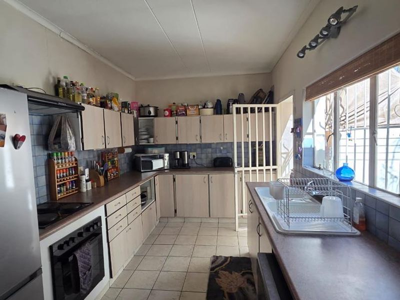 A functional kitchen featuring tiled flooring, ample built-in cabinetry, a tiled backsplash, and a built-in oven with hob.