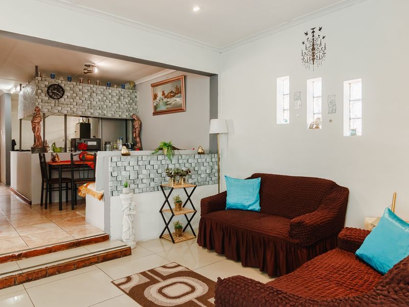 Open-plan living area featuring tiled floors, a decorative stone-clad partition wall, and unique glass block windows, creating a distinct transition between living and dining spaces.