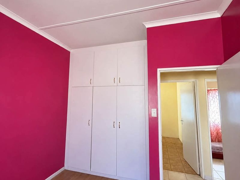 A bright bedroom featuring built-in cupboards, laminate flooring, and a coved ceiling, offering a clean and functional space.