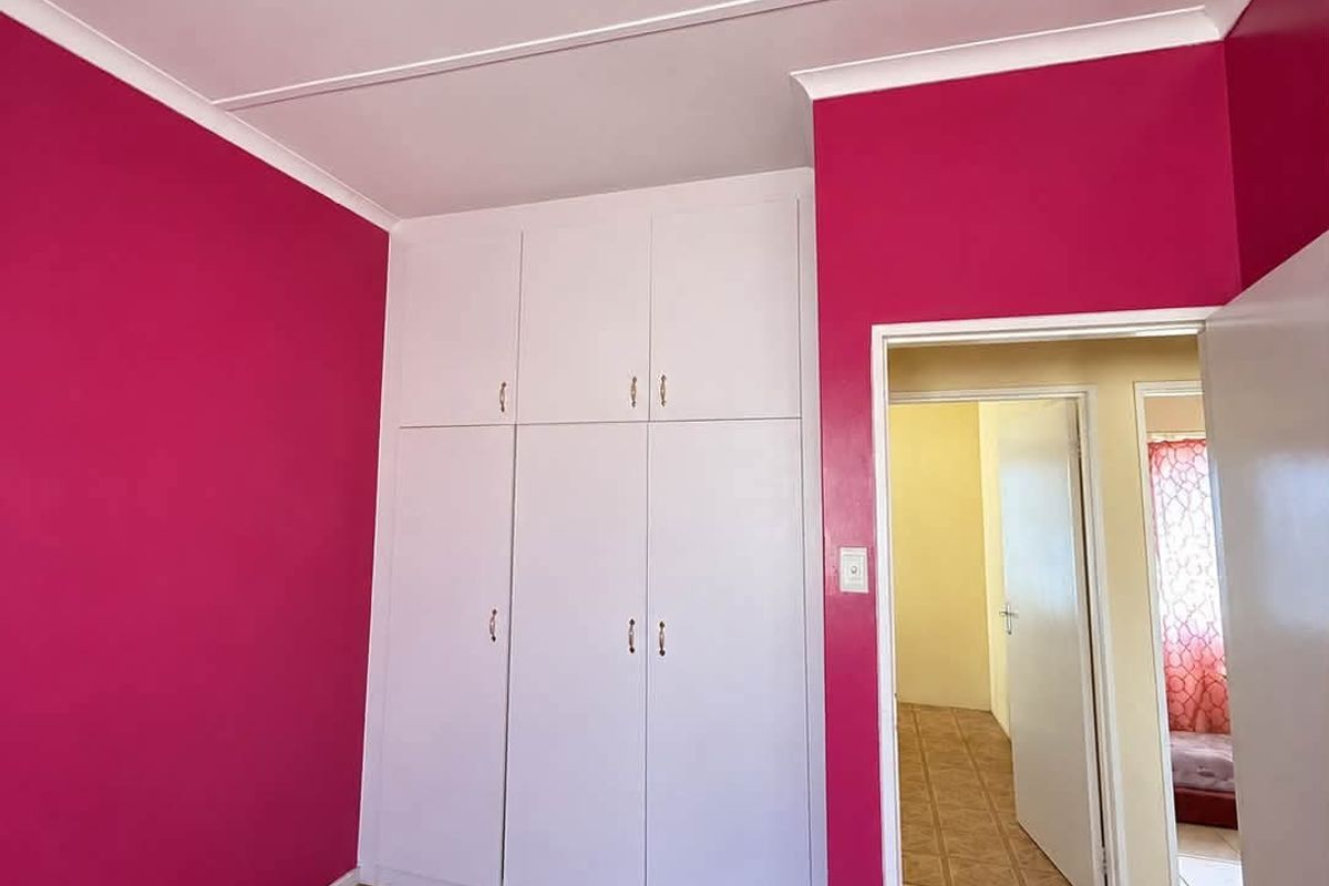 A bright bedroom featuring built-in cupboards, laminate flooring, and a coved ceiling, offering a clean and functional space.