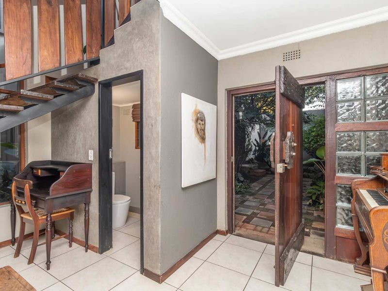 Entrance foyer featuring a staircase, tiled flooring, and direct access to a small bathroom and outdoor garden area.