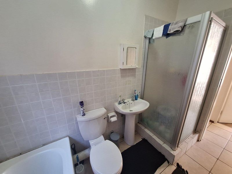 A functional bathroom featuring a pedestal basin, toilet, and a separate shower enclosure with tiled finishes.