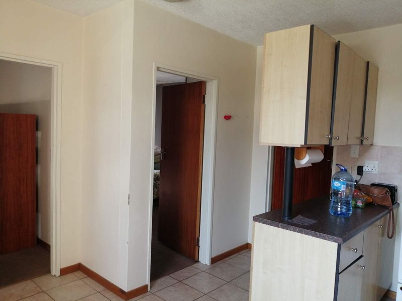 A functional kitchen area featuring laminate cabinetry and tiled flooring, providing access to adjacent rooms through internal doorways.