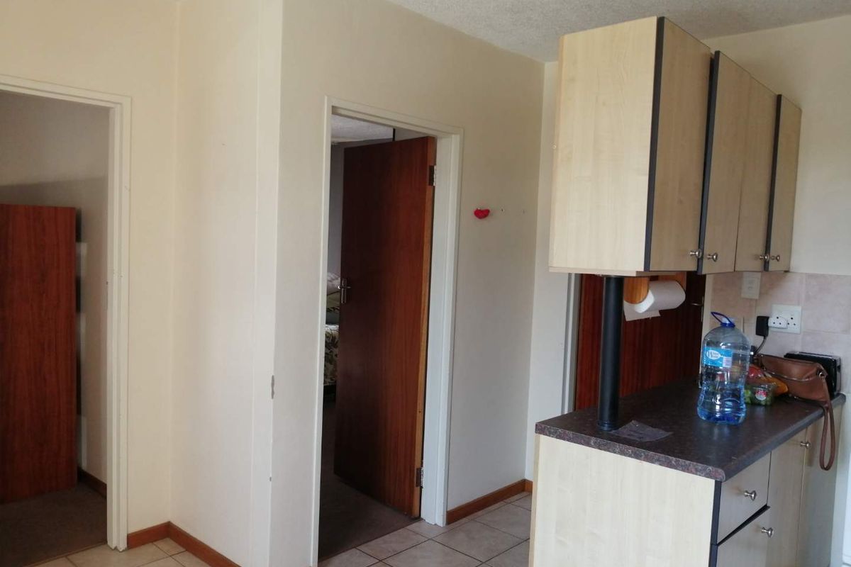 A functional kitchen area featuring laminate cabinetry and tiled flooring, providing access to adjacent rooms through internal doorways.