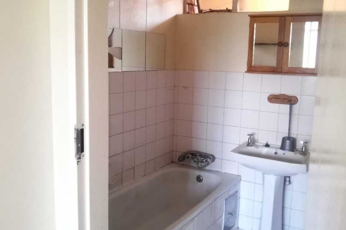 A dated bathroom featuring a standard bathtub, pedestal sink, and tiled walls, requiring modernization to improve its overall condition and aesthetic appeal.