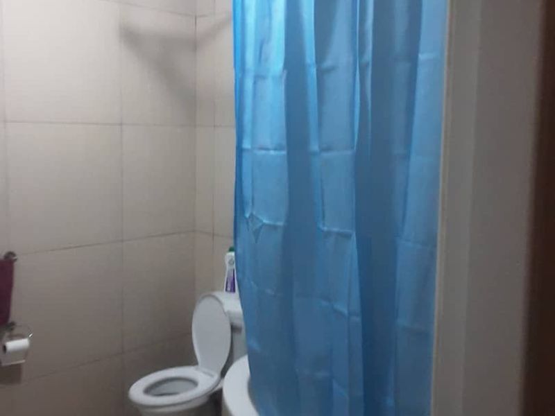 A functional bathroom featuring a bathtub with a shower curtain rail, tiled walls, and a standard toilet.