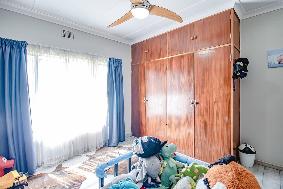 Bedroom featuring built-in wooden cabinetry, a ceiling fan, and tiled flooring, offering ample storage space.