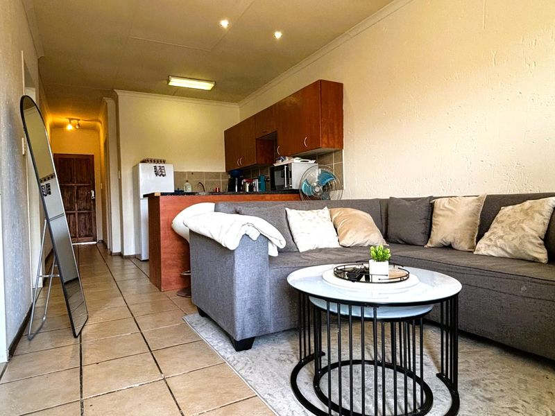 Open plan living area featuring tiled flooring and a compact kitchen with built-in cabinetry and counter space.