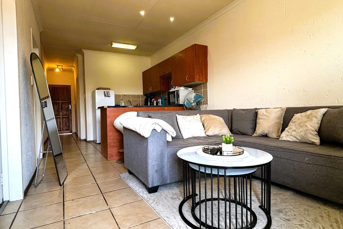 Open plan living area featuring tiled flooring and a compact kitchen with built-in cabinetry and counter space.