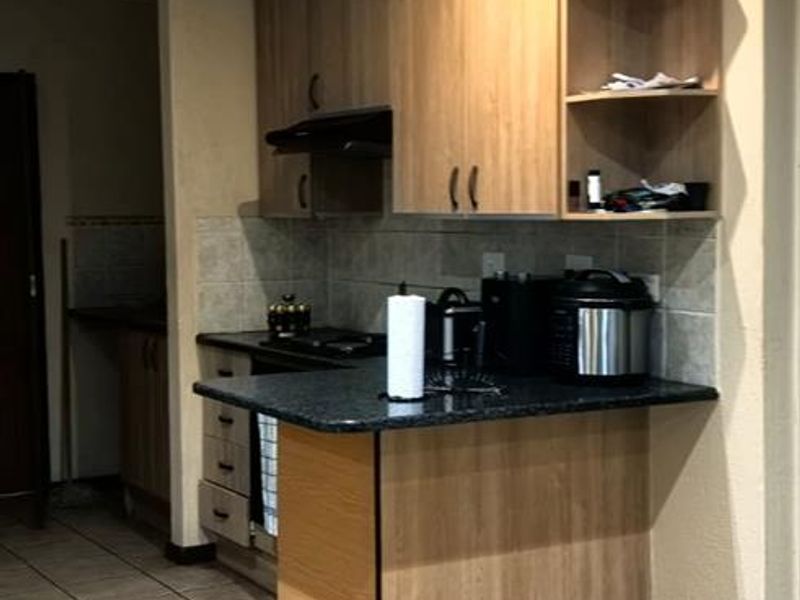 A functional kitchen featuring laminate cabinetry, granite countertops, and tiled flooring, offering a practical layout with integrated storage and workspace.